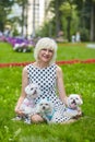 An adult woman in a park with three Maltese lapdogs
