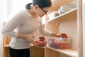 Adult woman picking food from storage cabinet in kitchen, storage with wooden shelves Royalty Free Stock Photo