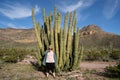 Adult woman picking her nose next to a large organ pipe cactus in Arizona