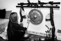 Adult woman playing gong- music therapy. Portrait of a happy woman striking a gong for meditation.