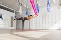 Adult woman practices balancing stick anti-gravity yoga position in studio