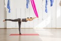 Adult woman practices balancing stick anti-gravity yoga position in studio