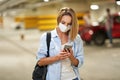 Adult woman in protection mask using cellphone in underground parking lot Royalty Free Stock Photo
