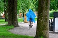 Adult woman riding bike in blue rain coat Orebro Sweden august 9 2023