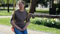 Adult woman riding swing sits with upset expression in park