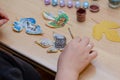 An adult woman`s hands hold a paint brush. Three drawings of animals are drawn on the leaves of a tree. An owl, a bear cub and a Royalty Free Stock Photo