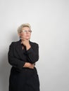 Adult woman with short hair, blonde. with glasses posing at the camera. There is a light background in the studio. Close-up