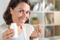 Adult woman showing vitamin pill looking camera at home Royalty Free Stock Photo