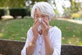 adult woman sitting in park and blowing nose Royalty Free Stock Photo