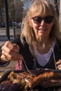 Adult woman skewering a pork chorizo with fork from an Argentinean barbecue Royalty Free Stock Photo