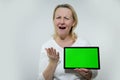 adult woman with a tablet in her hands is very surprised she does not like what she sees on it shows a green chromakey