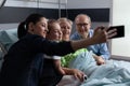 Family selfie with sick grandmother at clinic visiting areaNote