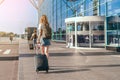 Adult woman tourist with hand luggage suitcase and backpack goes to the airport for journey. Woman ready to board the Royalty Free Stock Photo