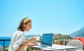 Adult woman using laptop computer drinking coffee enjoying working from resort cafe Royalty Free Stock Photo