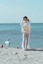 Woman in white swan costume yelling, sanding on sandy beach, near birds Royalty Free Stock Photo