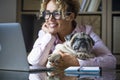 Adult woman work at laptop computer at home in office with her lovely best friend pug dog - concept of modern female people and Royalty Free Stock Photo