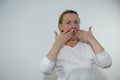 adult woman 40-50 years old covers her mouth with hands Do not say wide open raised eyebrows blond hair indignant white Royalty Free Stock Photo