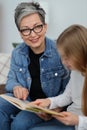 An adult woman reads a story in a book to a child Royalty Free Stock Photo