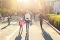 Adult young beautiful mother with cute adorable blond child girl having fun walking together at city park between people