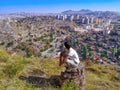 Adult young man squatting on a stone pillar and looking at the Ankara cityscape Turkey - view from the back. A tourist admires Royalty Free Stock Photo