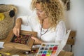 Adult young woman at home doing artwork with collorful beads - alternative work job economy business for trendy people - concept