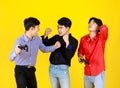 3 adults asian handsome men are relaxed by playing video game. Shooting in studio with isolated yellow background. In concept male Royalty Free Stock Photo