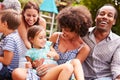 Adults and kids sitting on the grass in a garden Royalty Free Stock Photo