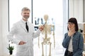 Adults posing near anatomy model in exam room of clinic