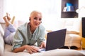 Adults and Technologies Concepts. Positive Caucasian Senior Woman Posing with Laptop and Headphones On Couch Indoors