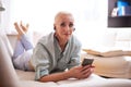 Adults and Technologies Concepts. Positive Caucasian Senior Woman Posing with Smartphone and Headphones On Couch Indoors