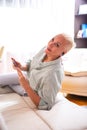 Adults and Technologies Concepts. Positive Caucasian Senior Woman Posing with Smartphone and Headphones On Couch Indoors