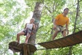 Adults walking across bridge suspended in trees