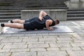 Young man doing a one arm push-up outdoors on concrete background