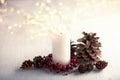 Advent candle with natural Christmas decoration and lights of garland   on white  rustic wooden  table. Toned image. Selective foc Royalty Free Stock Photo