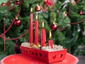 Advent greeting card. Four red burning candles in a beautiful candlestick. Decorated Christmas tree background. First candle in Royalty Free Stock Photo