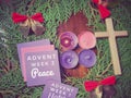 Advent week 2 peace text on paper with the second candle lit and wreath background. Second Advent Sunday concept.