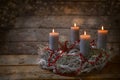 Advent wreath of branches with burning candles and red chain decoration, tradition in the time before Christmas, rustic wooden Royalty Free Stock Photo