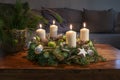 Advent, wreath with four burning white candles and Christmas decoration on a wooden table in front of the couch, festive home Royalty Free Stock Photo