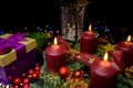 Advent wreath with four lit candles, gift box, snow globe and colored lights Royalty Free Stock Photo