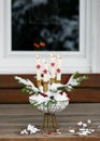 Advent wreath with four white burning candles and red wooden stars in a metal basket full of snow decorated with fir branches.