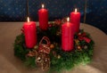 Advent wreath made of yew twigs, with four lighted red candles and ribbon on a table at home Royalty Free Stock Photo