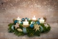 Advent wreath series number four with lit candles, blue Christmas baubles and decoration on a rustic wooden snowy background, Royalty Free Stock Photo