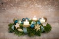 Advent wreath series number three with lit candles, blue Christmas baubles and decoration on a rustic wooden snowy background, Royalty Free Stock Photo