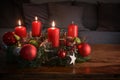 Advent wreath with three burning red candles and Christmas decoration on a wooden table in front of the couch, festive home decor Royalty Free Stock Photo