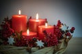 Advent wreath from willow wicker with four lighted red candles, cinnamon star cookies and berries, holiday decoration for