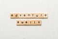 Adventure awaits word written on wood block. Adventure awaits text on cement table for your desing, concept Royalty Free Stock Photo