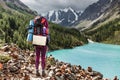 Backpacking woman enjoying view of majestic blue mountain lake in Altai
