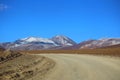 Adventure in the Bolivian Andes desert. Dusty road and mountains. Royalty Free Stock Photo