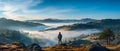 Adventure and Exploration theme: Candid shot of a traveler on a mountain peak, gazing at the majestic foggy landscape Royalty Free Stock Photo