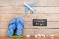 blackboard with text & x22;Travel tips& x22;, plane, seashells on brown wooden background Royalty Free Stock Photo